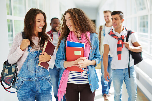 teenage girls walking along college corridor