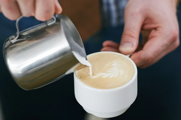 Barista añadiendo leche en una taza de café con leche — Foto de Stock