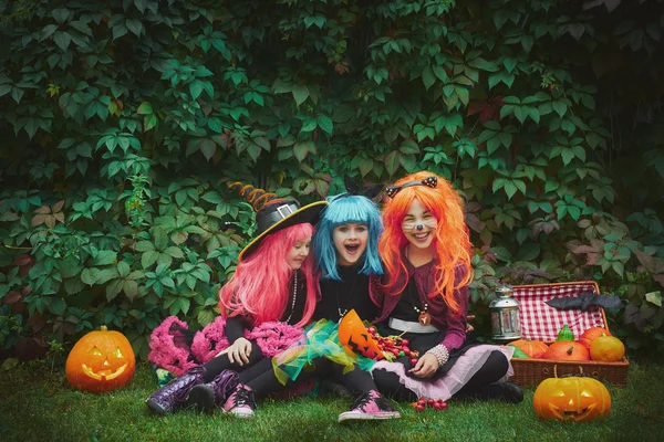 Meisjes in Halloween kleding met pompoenen en snoep — Stockfoto