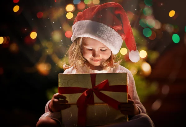 Девушка в шапке Санта смотрит на подарок — стоковое фото