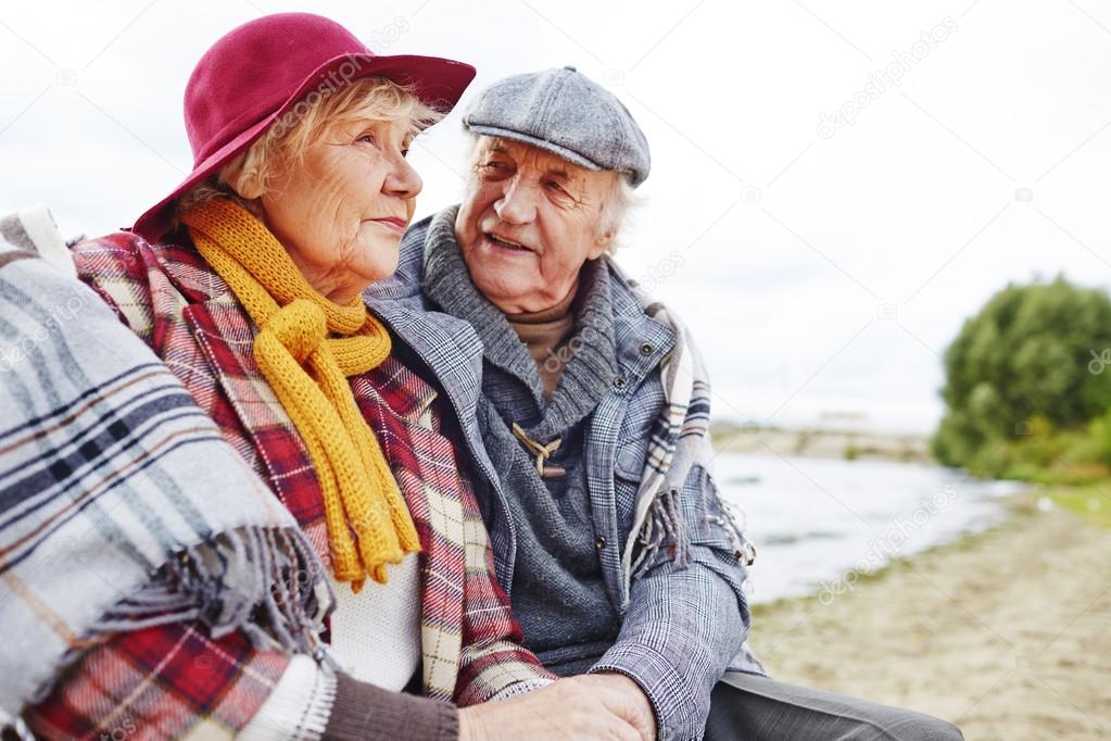 happy seniors sitting by seaside