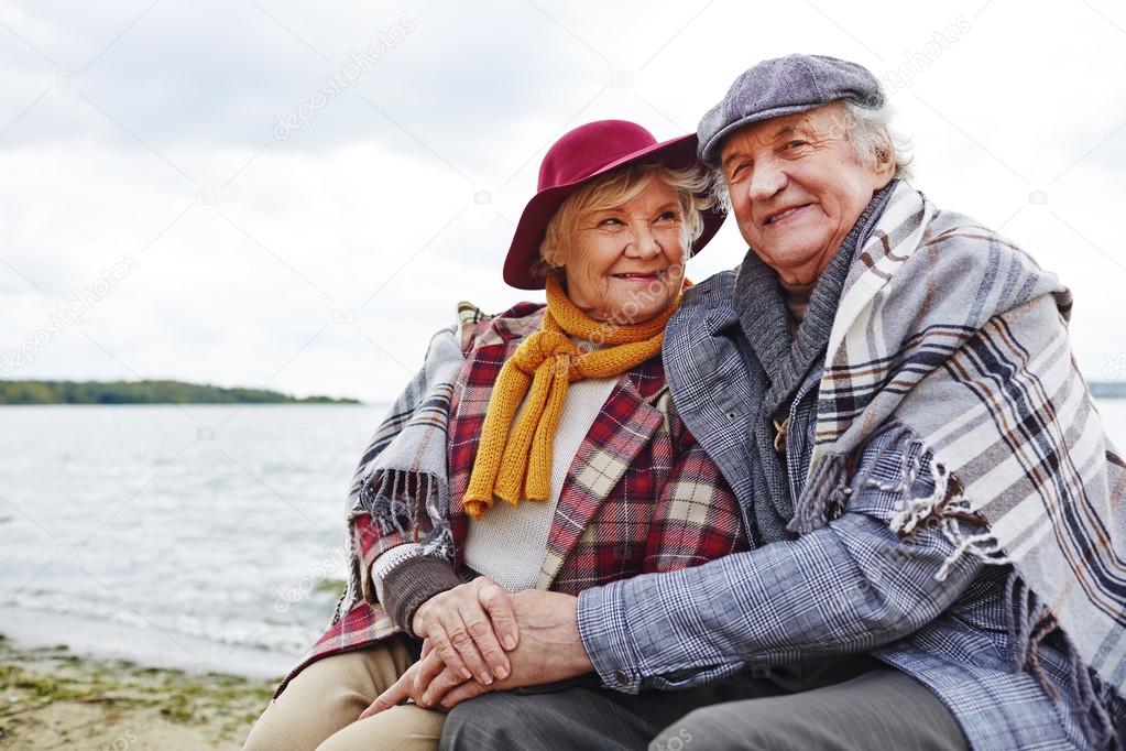 happy seniors sitting by seaside