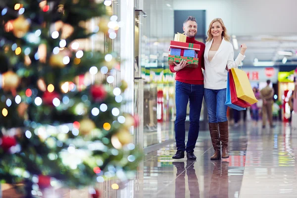 Pareja con regalos de Navidad en el centro comercial —  Fotos de Stock