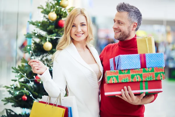 Pareja con regalos de Navidad en el centro comercial — Foto de Stock