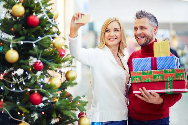 Couple with presents making selfie in mall — Stock Photo, Image