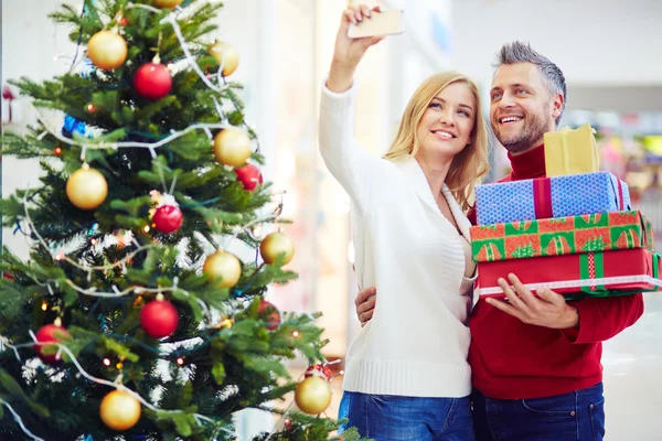 Casal com presentes fazendo selfie no shopping — Fotografia de Stock