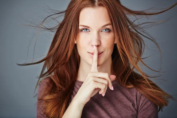 Vrouw met haar wijsvinger door de mond — Stockfoto