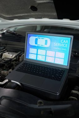 Otomotiv tamir için araç diyagramı ve bakım simgeleri ile tanısal arayüzü gösteren, motor bölmesinde konumlandırılmış dijital araba servis kontrol ekranını gösteren dizüstü bilgisayar
