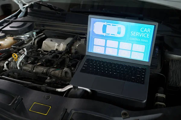 Otomotiv atölyesinde araç bakım ve onarım için tanısal arayüzü gösteren, açık motor bölmesine yerleştirilmiş kontrol paneli ekranını gösteren dizüstü bilgisayar