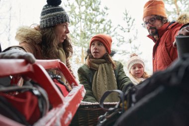 Beyaz aile kış ormanlarında kızak hazırlıyor, hepsi kalın kıyafetler ve şapkalar giyiyor, birbirleriyle etkileşime geçiyorlar.
