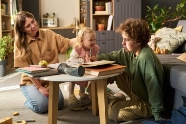 Kafkasyalı genç bir kadın beyaz bir kızla ve beyaz bir çocukla etkileşime giriyor. Masada oturuyor ve rahat bir ev ortamında birlikte yazı yazıyor.