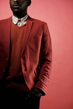 Kırmızı arka planda elleri ceplerinde, gözleri görünmeyen, tanınmayan siyah adam portresi.