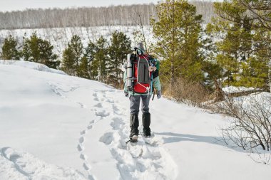 Beyaz adam, karlı ormanda yürüyüşe çıktı. Sırt çantasındaki küçük beyaz çocuğu taşıdı. Karla kaplı patika boyunca yürüdü.