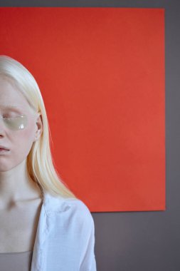 Gözlerinin altında kırmızı ve gri arka planda duran kolajen bantları olan modern beyaz kadının dikey stüdyo portresi