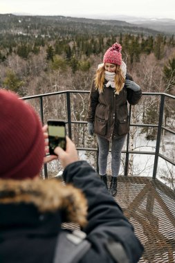 Akıllı telefonlu çiftçi, dağların yüksek noktasında birlikte seyahat ederken güzel bir kadının fotoğrafını çekiyor.