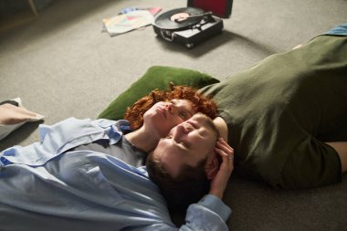 Kafkasyalı genç kadın ve Kafkas genci yerde birlikte yatıp plakçalar dinliyorlar, kafaları birbirine yakın, kadınlar yukarıya bakıyor, erkekler gözleri kapalı dinleniyor.