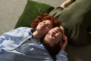 Genç aşıklar başlarını yeşil yastığa koyup yerde yatıyorlar, gözleri kapalı rahatlıyorlar, barışçıl ifadeler sergiliyorlar.