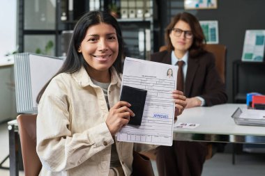 Elinde pasaport, elinde vize başvurusu formu ile gülümseyen genç İspanyol kadın portresi.