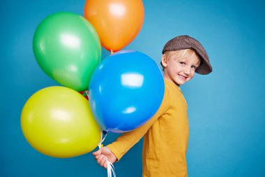 Küçük çocuk holding renkli balonlar