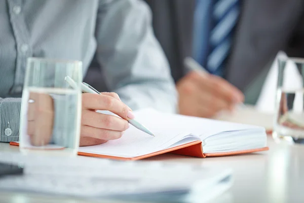 Hand met pen schrijven in notitieblok — Stockfoto