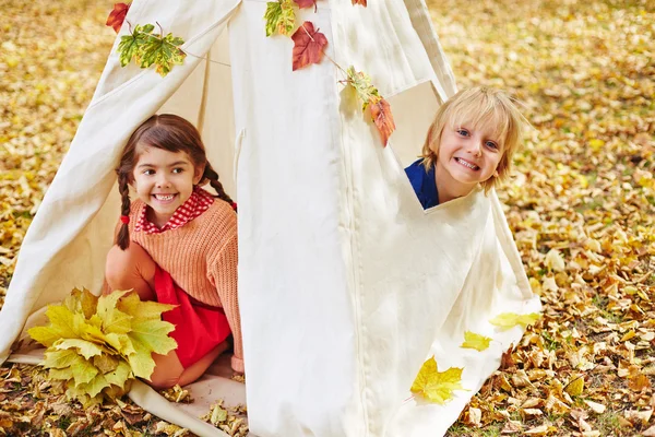 Barnen sitter i tält i höst park — Stockfoto