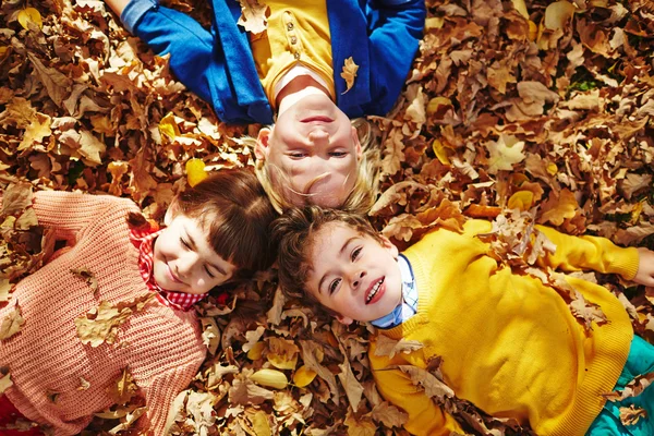 Kinder liegen auf herbstlichem Boden — Stockfoto