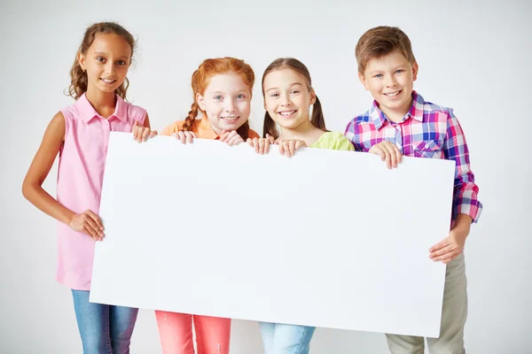 Schoolkids holding blank paper — Stock Photo, Image