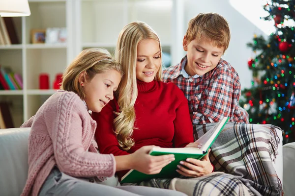 Kvinnan, hennes dotter och son läsa bok — Stockfoto