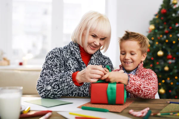 Großmutter hilft ihrem Enkel beim Binden von Geschenken — Stockfoto