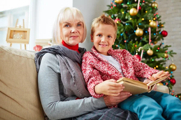 Mature woman holding her grandson with book — Stock Photo, Image