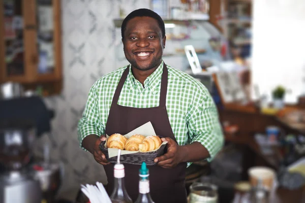 Mannen i uniform håller färska croissanter — Stockfoto