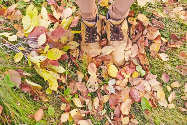 Pernas em botas em folhas de outono — Fotografia de Stock