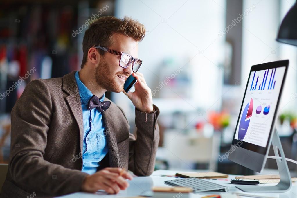 businessman speaking on the phone while looking at computer