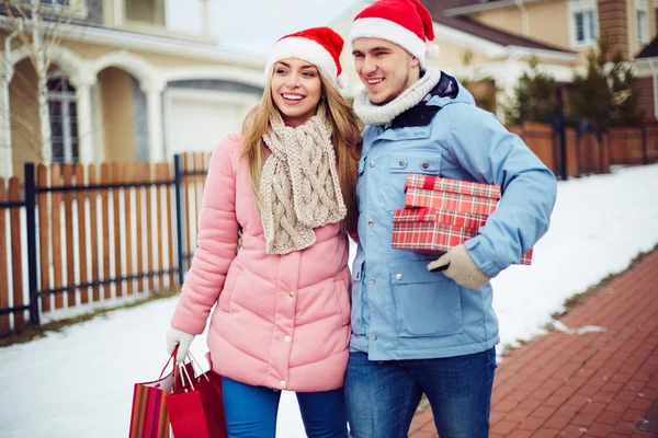 Paar in Santa caps geschenkdozen uitvoering — Stockfoto