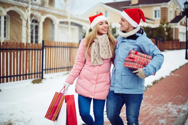 Paar in Santa caps geschenkdozen uitvoering — Stockfoto
