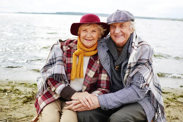 Äldre par i varma kläder på stranden — Stockfoto