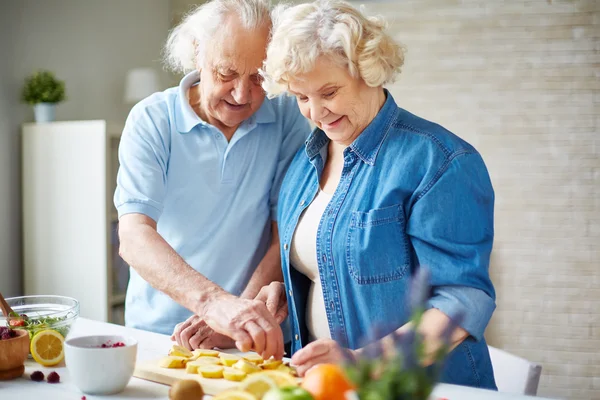 Uomo e donna anziani che tagliano frutta — Foto Stock