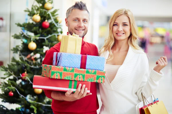 Pareja con regalos de Navidad en el centro comercial — Foto de Stock