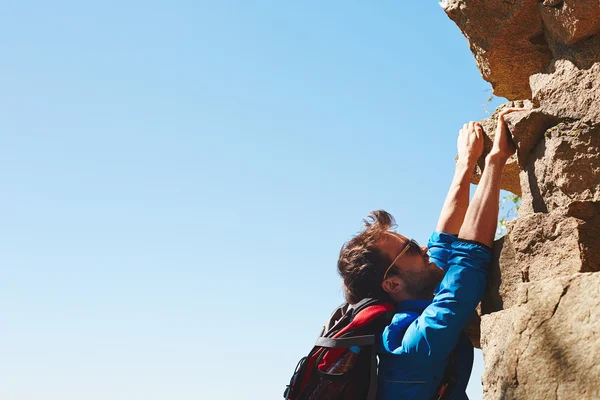 Hombre escalando en la cima de la roca — Foto de Stock