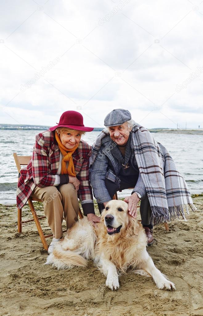 senior couple with dog resting on beach