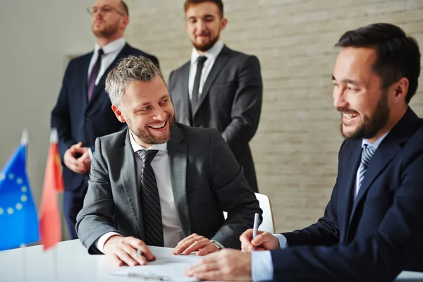 Vrolijke zakenlieden zitten aan de tafel — Stockfoto