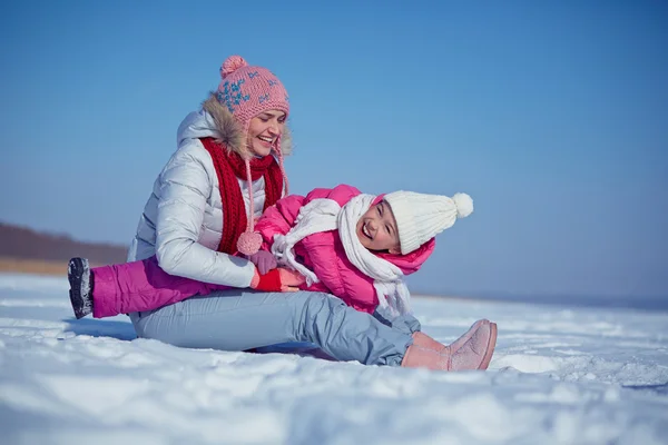Женщина в зимней одежде играет со своей дочерью — стоковое фото