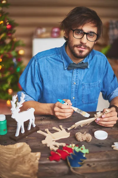 Young man painting Christmas symbols — Stock Photo, Image