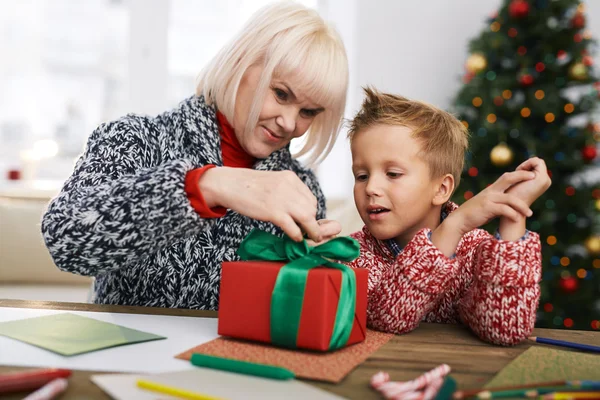 Frau hilft ihrem Enkel beim Binden von Geschenkschachteln — Stockfoto