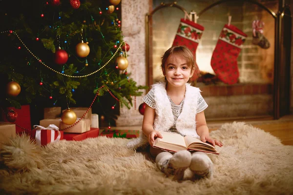 Meisje met boek over Kerst avond — Stockfoto