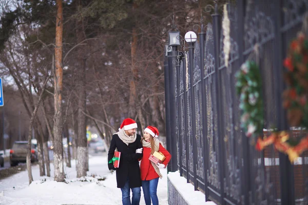 Casal em chapéus de Santa com presentes de Natal — Fotografia de Stock
