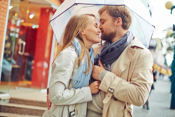 Casal beijando uns aos outros durante a chuva — Fotografia de Stock