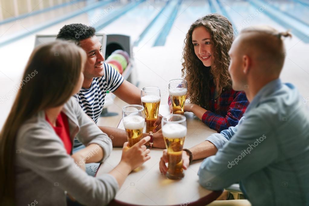 friends drinking beer in bowling club