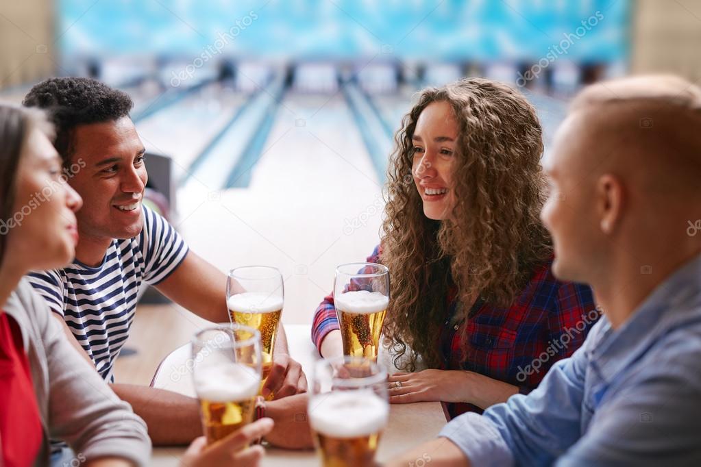 friends refreshing with beer after bowling