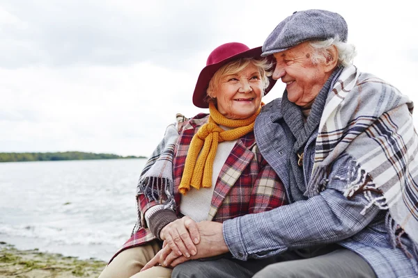 Aanhankelijk senioren zittend aan kust — Stockfoto